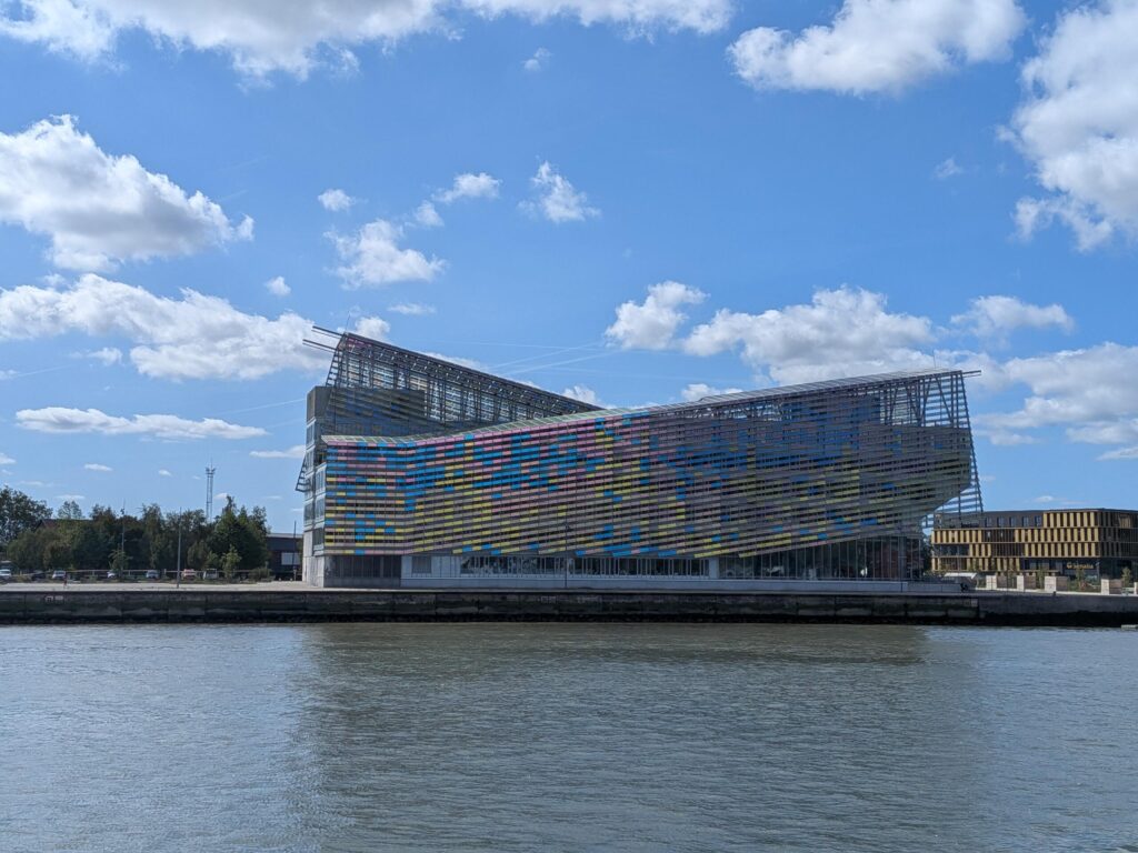 Un bâtiment multicolore en forme de vague en bord de rivière