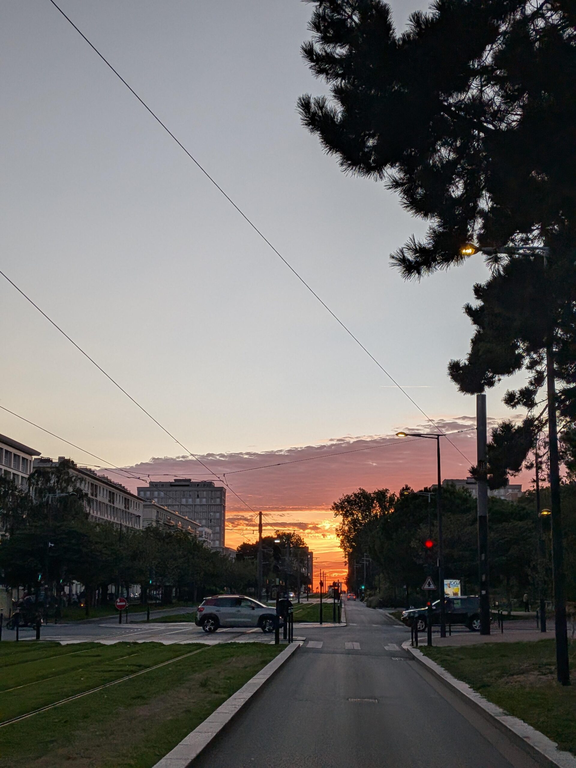 Grande avenue en ville et dans la perspective au fond le soleil couchant