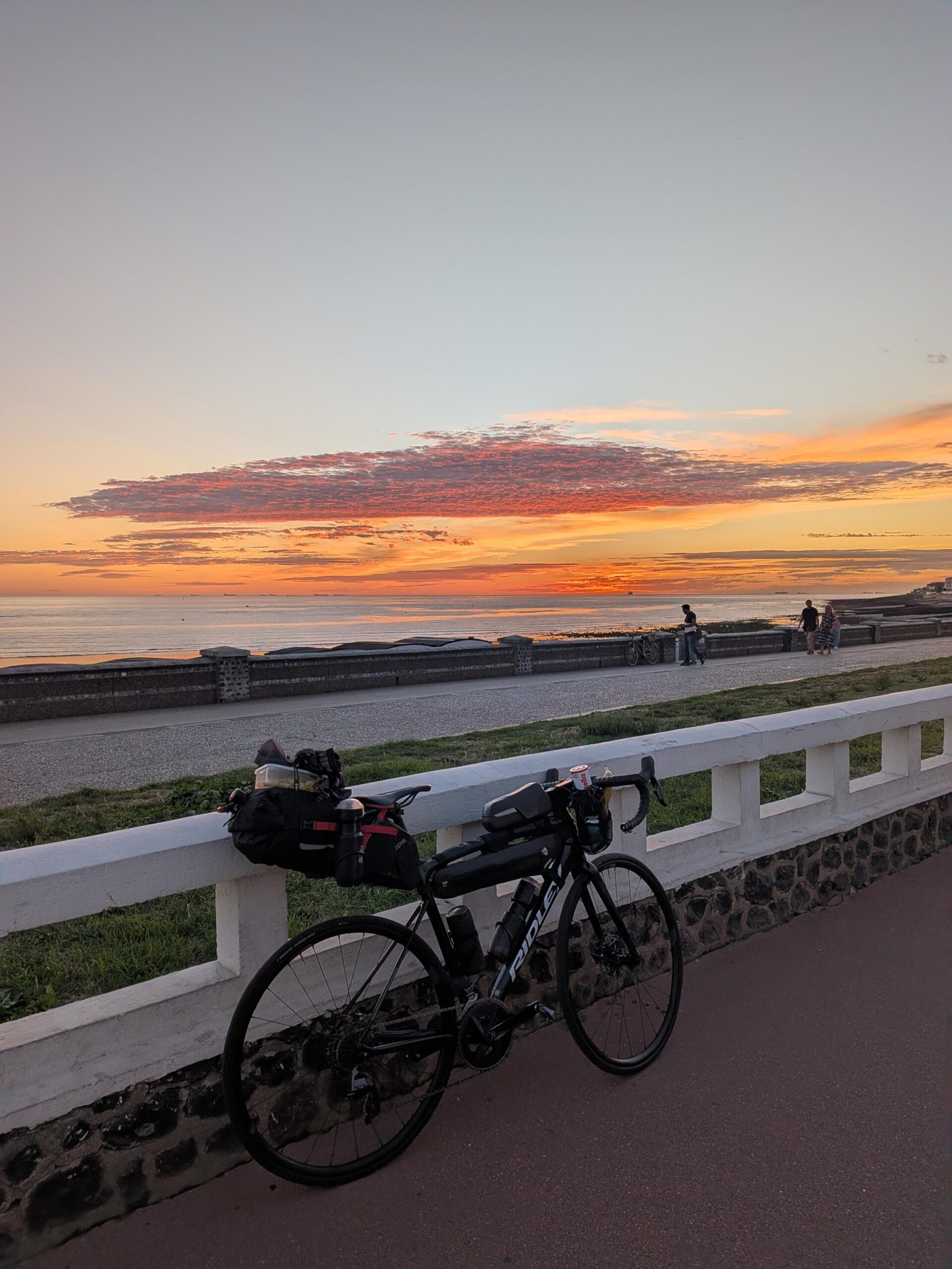 Couché de soleil en bord de mer, au premier blanc un vélo posé sur un mur blanc